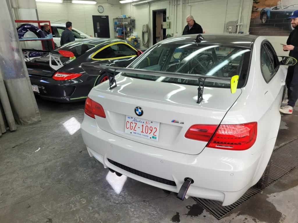 White BMW M3 in the shop with technicians in the background