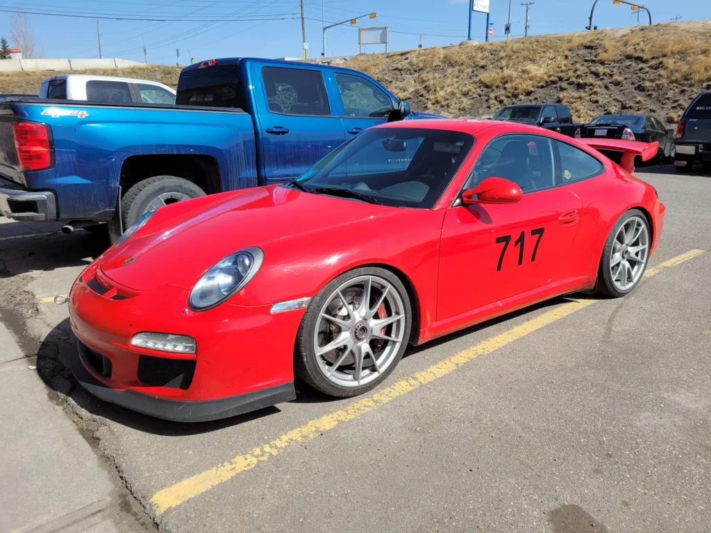 Red Porsche 911 GT3 with track number 717 in a parking lot
