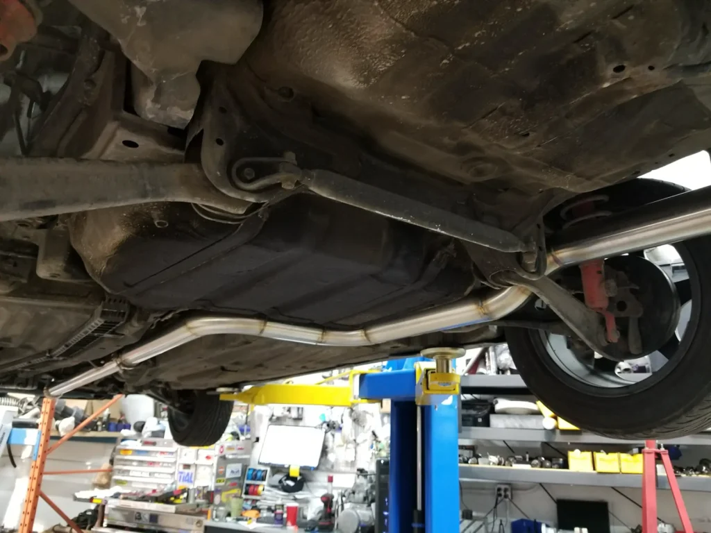 Underside of a car on the lift showing the rear brake and suspension
