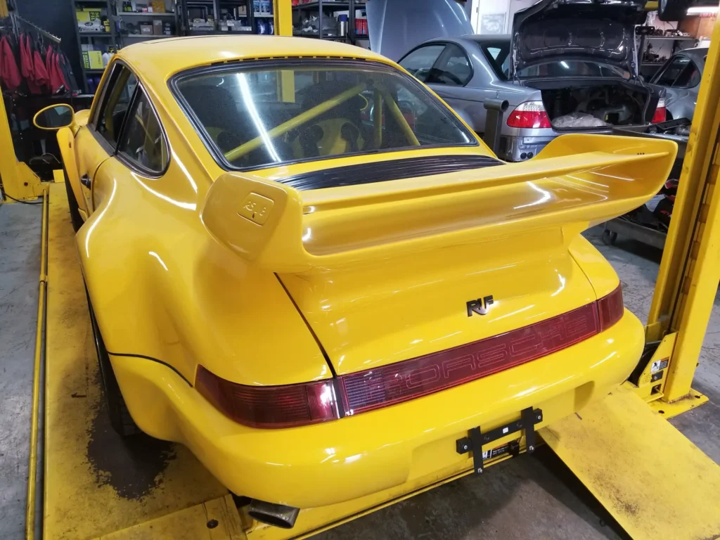 Yellow Porsche 964 on a four-post lift at Alpine Autowerks