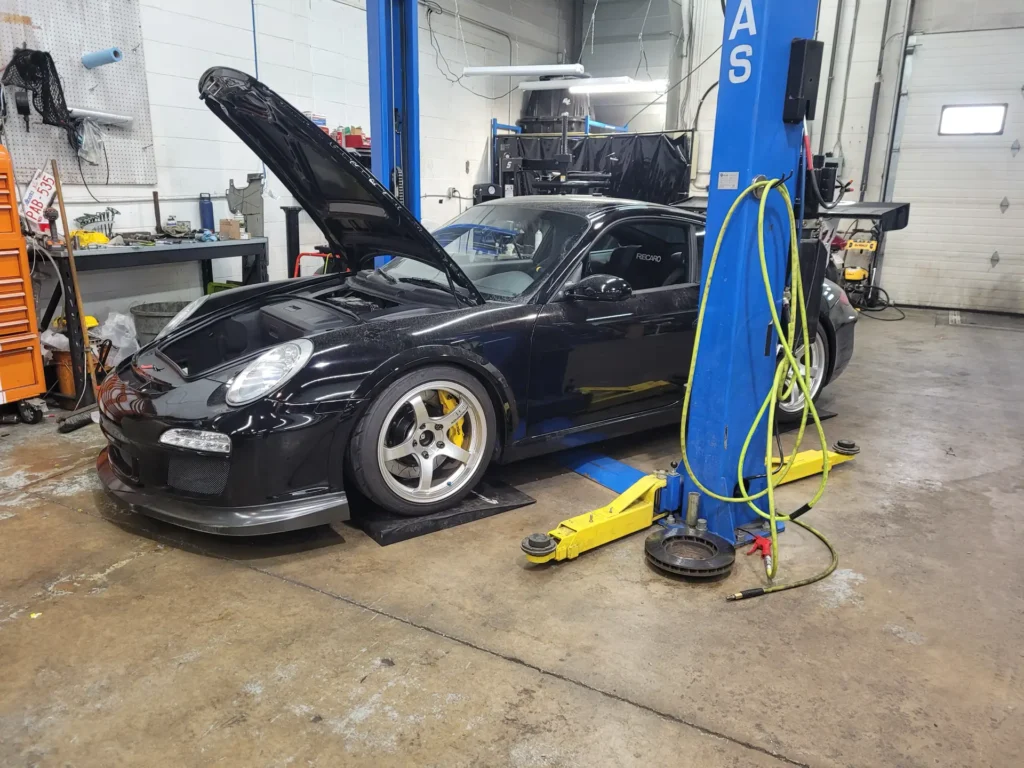 Black Porsche 911 with the hood open in a service bay at Alpine Autowerks