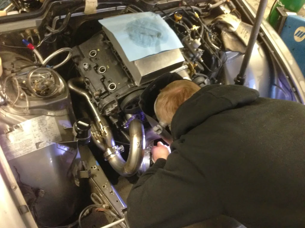 Technician tracing a fault in the engine bay of a car at Alpine Autowerks