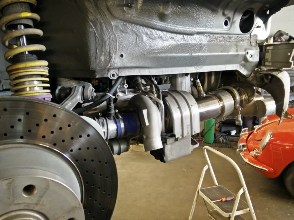 Coilover, drilled brake rotor and turbo plumbing under a car on the lift