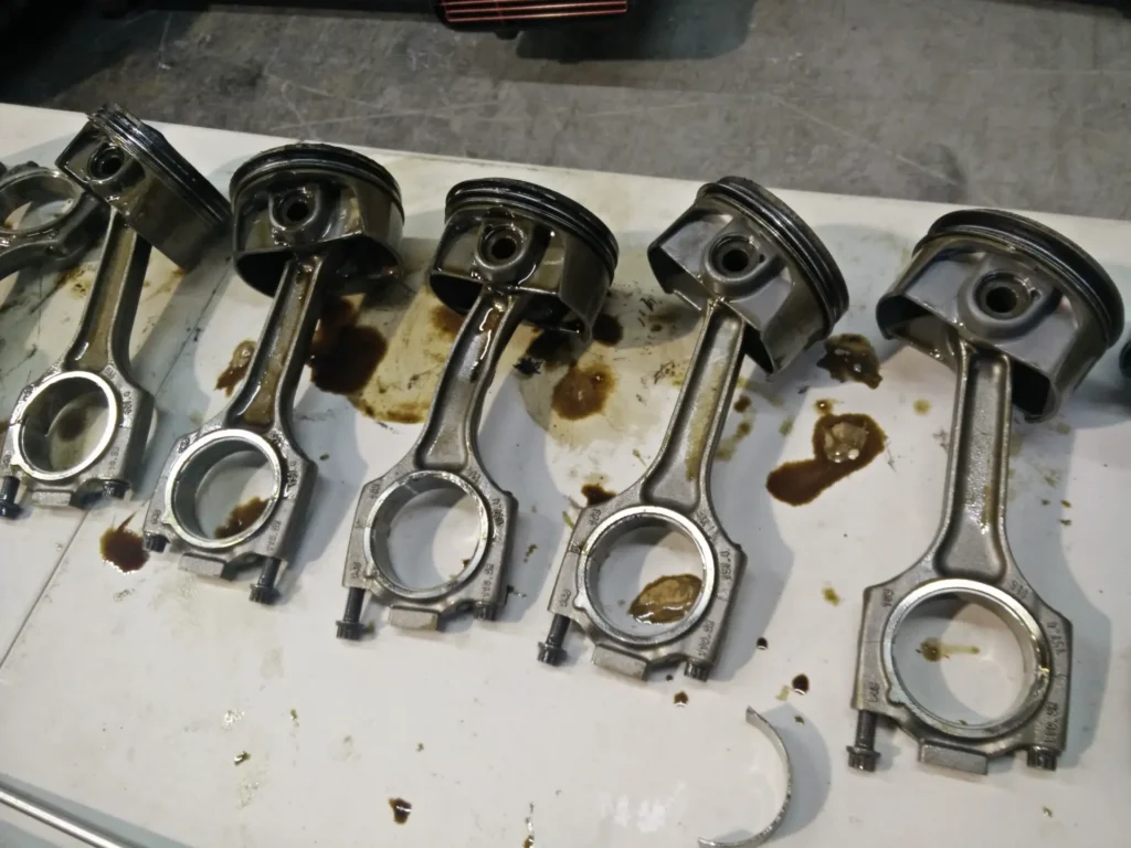 Used pistons and connecting rods laid out during an engine teardown