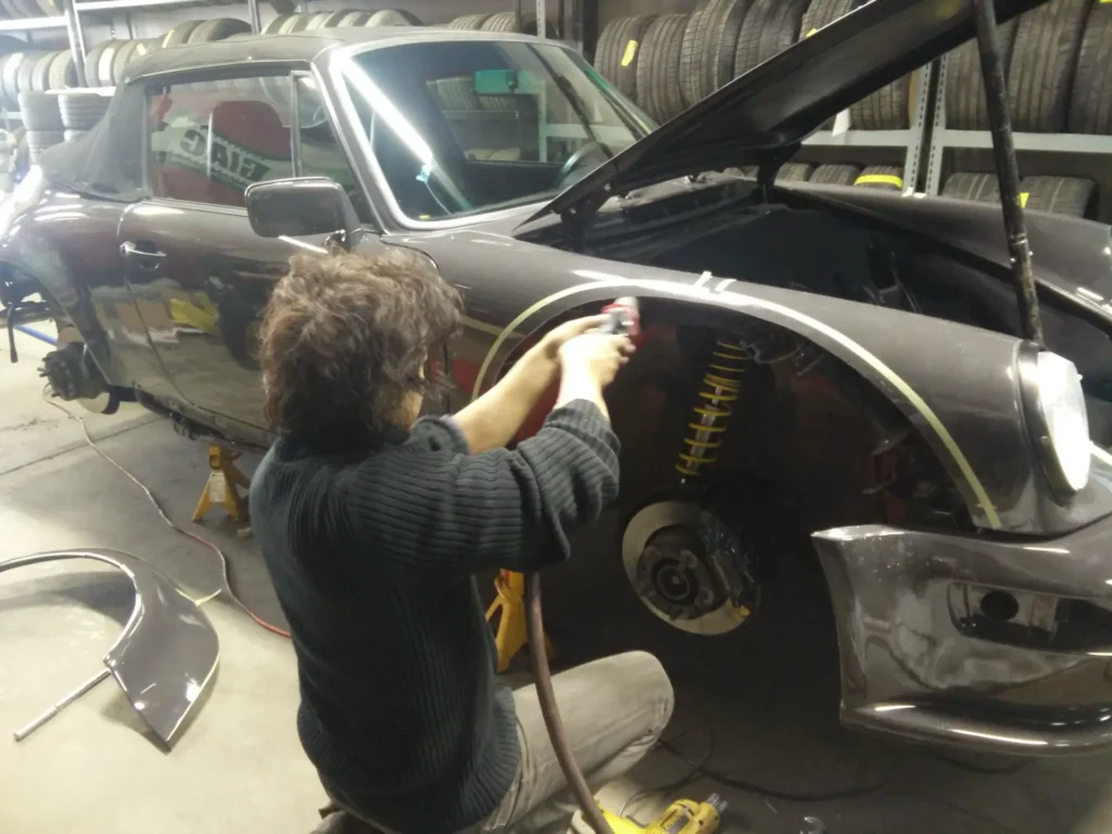 Technician working at the front wheel arch of a car with the wheel removed
