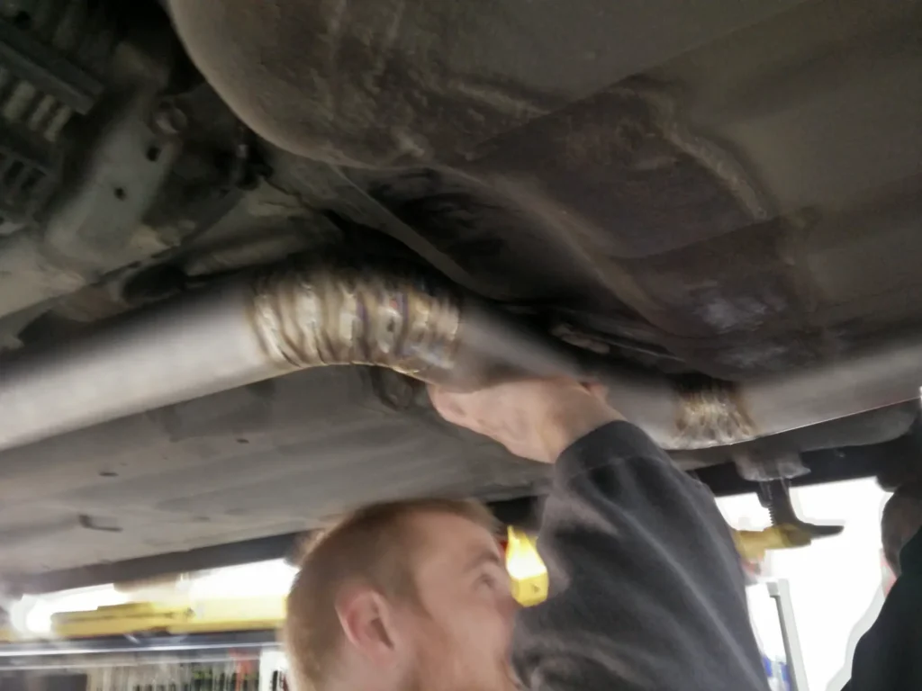 Technician working under a car on a lift at Alpine Autowerks